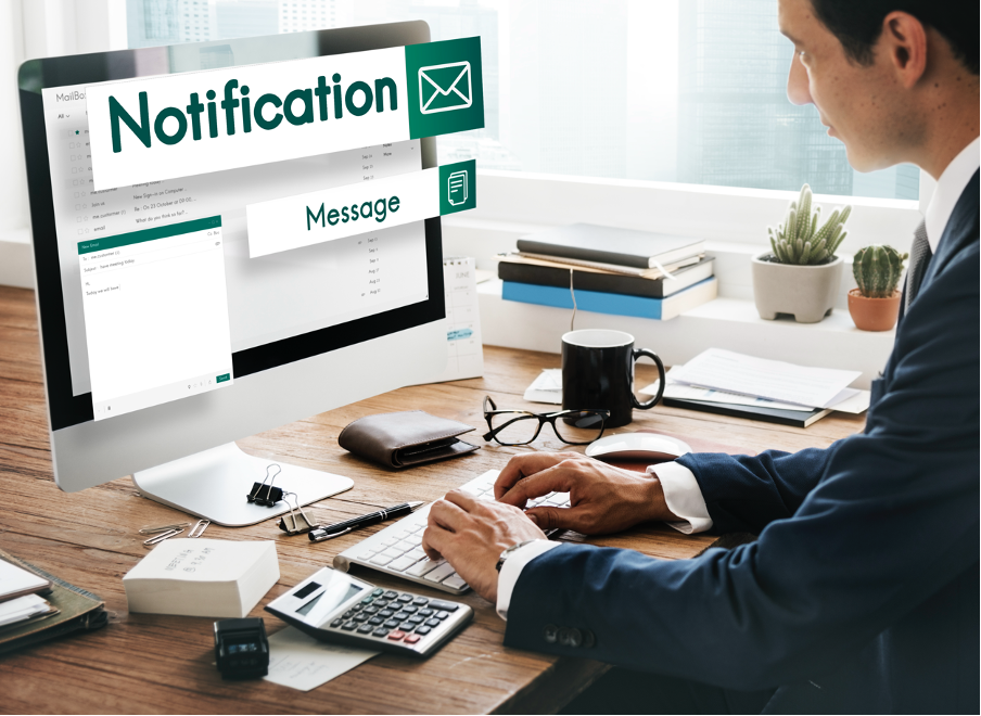 Man sitting in in front of a desktop receiving email notifications